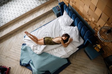 İç çamaşırlı, yatakta poz veren güzel esmer manken.