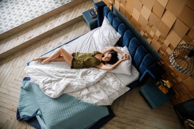 İç çamaşırlı, yatakta poz veren güzel esmer manken.