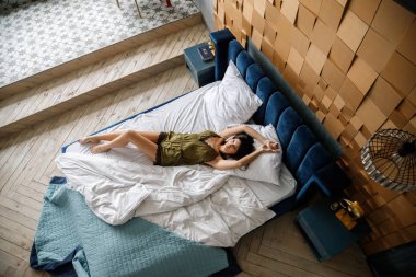 İç çamaşırlı, yatakta poz veren güzel esmer manken.