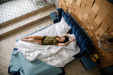 İç çamaşırlı, yatakta poz veren güzel esmer manken.