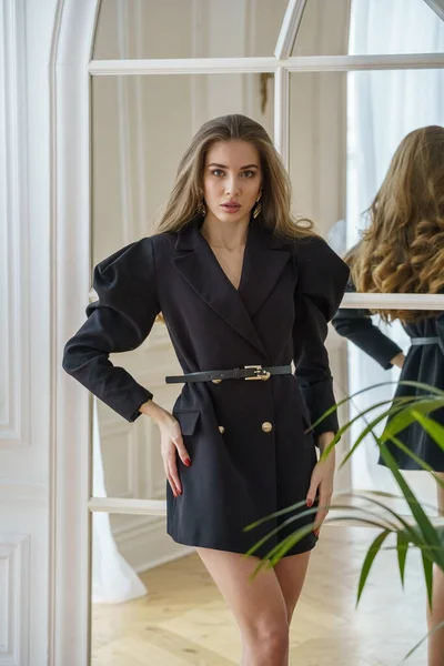 Fiatal Gyönyörű Modell Fekete Kabátban Magassarkúban Áll Tükör Mellett Apartmanokban — Stock Fotó