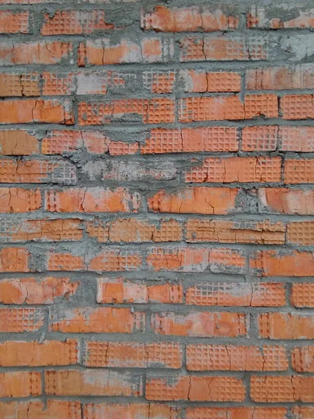 Dark red brick wall with traces of cement, texture background for design. A pattern of a weathered old cracked brick wall. Brick work wall from old building architecture