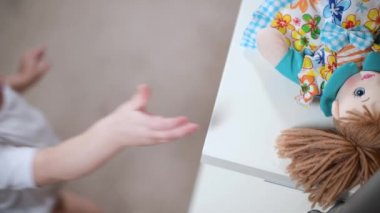 Küçük bir kız oyuncak bebeğini raftan alıp yanında götürüyor.