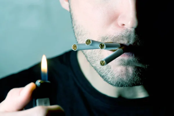 En man med ett halvt upplyst ansikte ser skeptisk och cigaretter sticker ut ur munnen, Inga ögon — Stockfoto