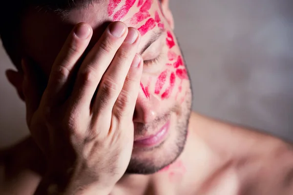 Nahaufnahme eines Mannes mit Lippenstiftspuren im Gesicht, die sein Gesicht mit der Handfläche bedecken — Stockfoto