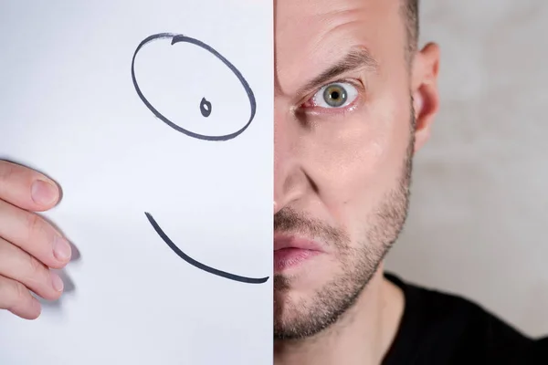आदमी अपने चेहरे को चित्रित मुस्कान के साथ कागज के टुकड़े के साथ कवर करता है — स्टॉक फ़ोटो, इमेज