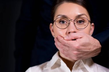 Bir erkeğin avuç içi kızın ağzını kapatır.