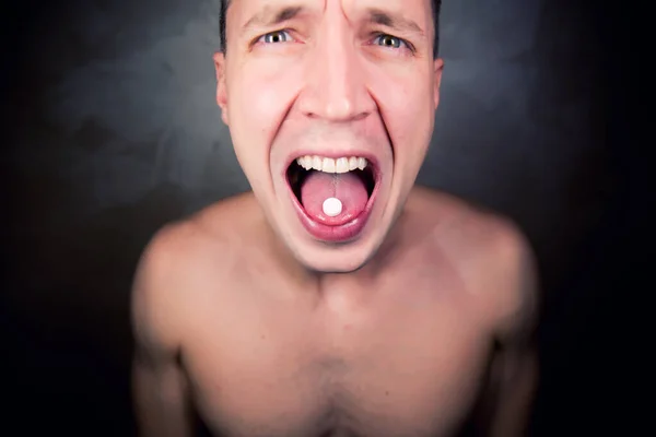 옷 이 없는 남자가 알약을 놓인 혀를 보여 주고 있다 — 스톡 사진