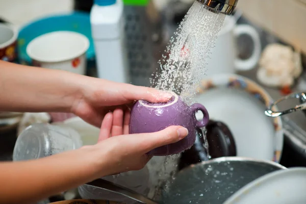Tazze di lavaggio sotto l'acqua corrente sullo sfondo di un lavello da cucina — Foto Stock