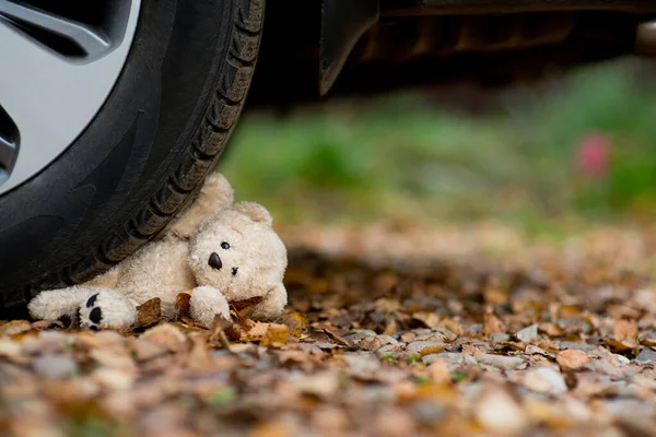 Teddy maci az autó kereke alatt — Stock Fotó