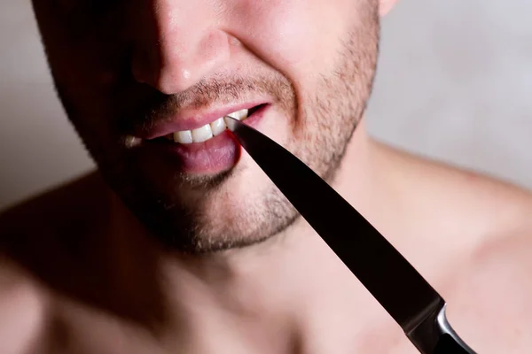 Hombre limpia el espacio entre sus dientes con un cuchillo, de cerca —  Fotos de Stock