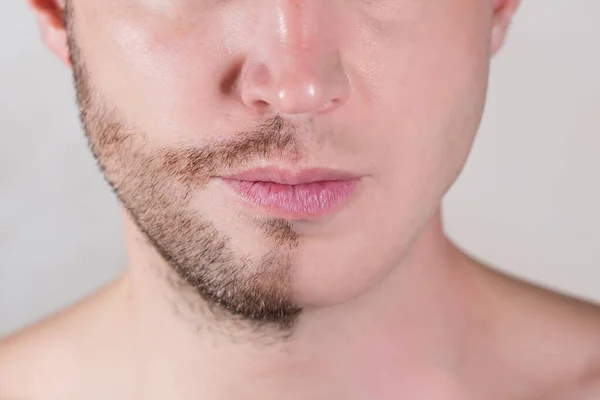 The lower half of the man 's face is only half shaved — стоковое фото
