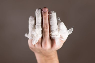 Ortası hariç tüm parmaklarının bandajlı olduğu bir erkek eli.