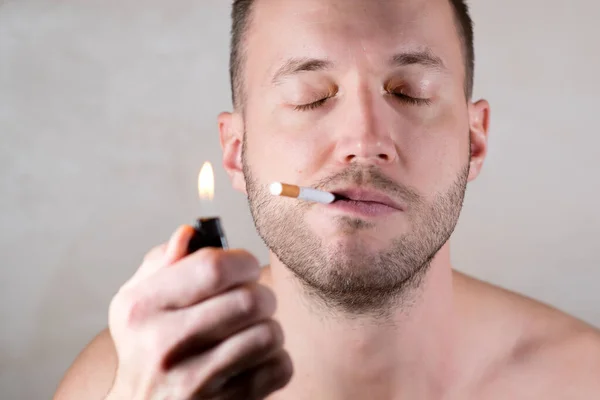 Sleepy man with closed eyes trying to wake up lighting a cigarette with the wrong side — Stok fotoğraf