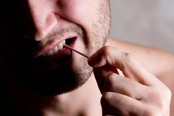 Homem limpa o espaço entre os dentes com um palito, de perto — Fotografia de Stock