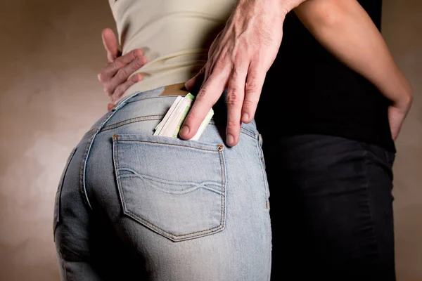 Chico pone dinero en el bolsillo trasero de una chica abrazándola — Foto de Stock