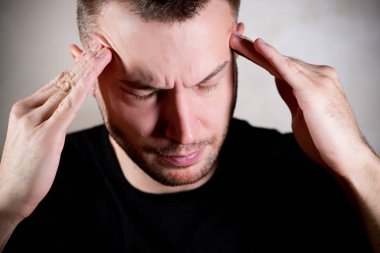 Adam gözleri kapalı başını tutuyor.