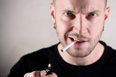 Sert yüzlü vahşi bir adam sigarasını yakmak üzere.