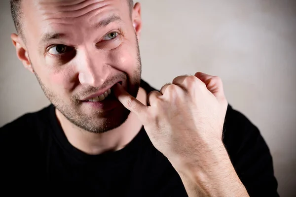 Muž čistí prostor mezi zuby prstem — Stock fotografie