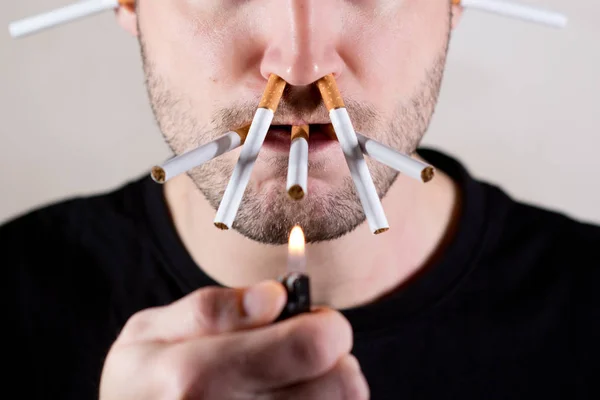 Egy férfi borotválatlan arcának alsó fele, és egy csomó cigaretta a szájában és az orrában. — Stock Fotó