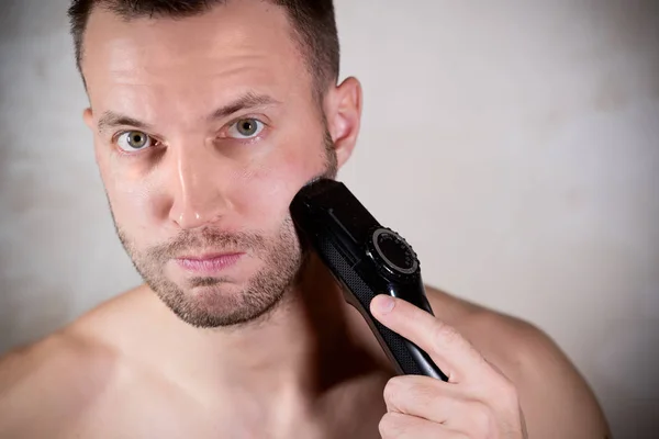 Jonge man op het punt om zijn korte baard te scheren met een trimmer — Stockfoto