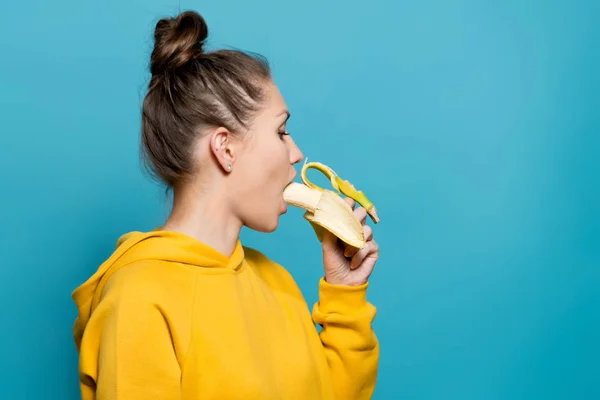 Mooi meisje zetten een banaan in haar mond — Stockfoto