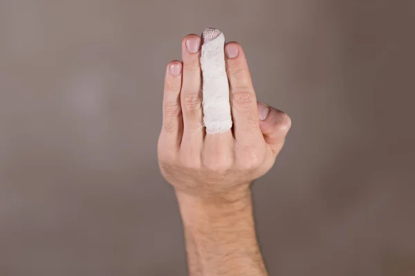Mão masculina em que o dedo médio é enfaixado — Fotografia de Stock