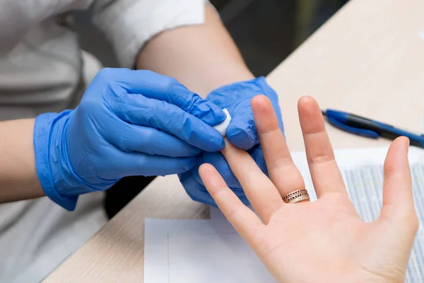 Un médico prepara el dedo del paciente para la toma de muestras de sangre — Foto de Stock