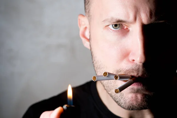En man med ett halvljust ansikte ser skeptisk ut och cigaretter sticker ut ur munnen, kopiera utrymme — Stockfoto