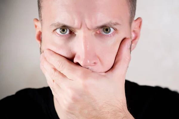 En man stänger munnen med handflatan — Stockfoto