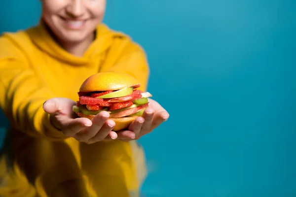 Gezonde hamburger van bessen en fruit ligt op de handen van een meisje dat in defocus — Stockfoto