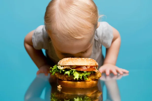 Mädchen vergrub ihr Gesicht in einem Burger, der auf dem Tisch lag — Stockfoto