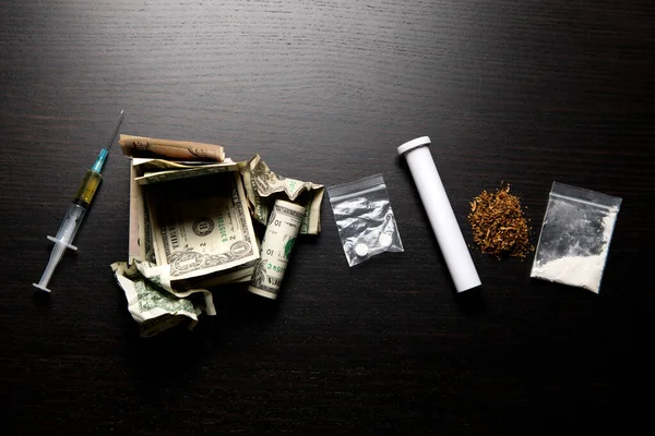 Een rij van verschillende drugs en verkreukelde dollars op tafel — Stockfoto