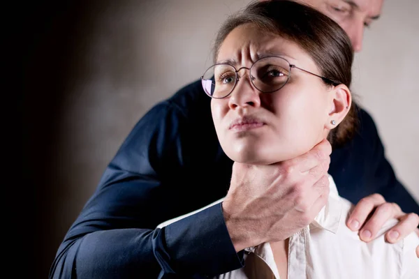 A menina sofre violência de um homem forte que a agarrou pela garganta — Fotografia de Stock