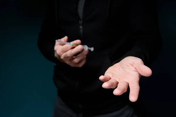 Mann hält eine Spritze mit einem Medikament in der Hand und streckt seine leere Hand aus, um auf eine Bezahlung für das Medikament hinzuweisen — Stockfoto