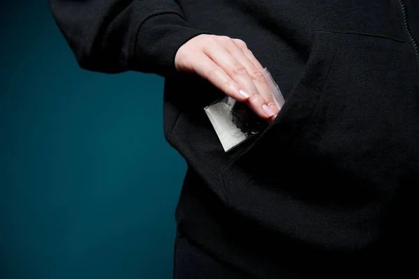 Uma mão feminina tira um saco de heroína ou cocaína de um bolso — Fotografia de Stock