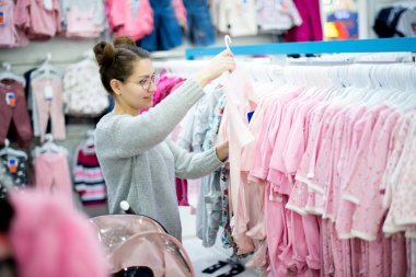 Genç bir kadın bebeği için sürgüleri seçer.