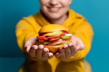 Gülümseyen kız et ve ekmek olmadan sağlıklı bir burger yemeyi öneriyor. Meyveli sandviç.