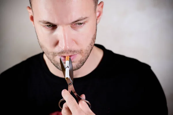 Neoholený muž držící cigaretu nůžkami — Stock fotografie