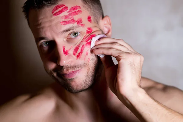 Schöner Mann sieht unzufrieden aus und versucht, die Spuren von Küssen mit einer Serviette zu tilgen — Stockfoto
