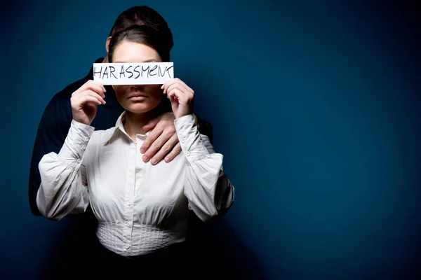 A lány becsukja a szemét egy darab papírral a felirattal zaklatás, mögötte egy férfi — Stock Fotó