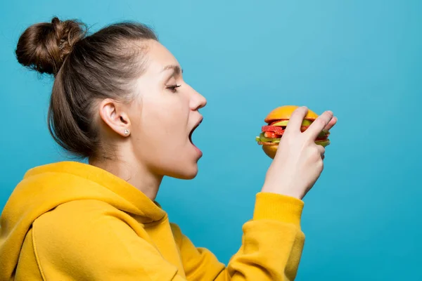 Jonge vrouw op het punt om een vegetarische burger gemaakt van fruit en bessen eten — Stockfoto
