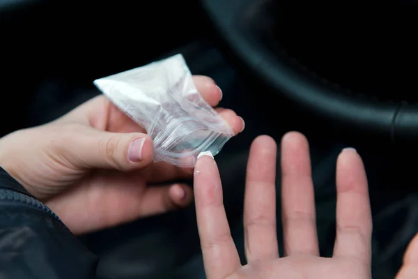 Meisje neemt een dosis cocaïne uit de verpakking met een vingernagel — Stockfoto