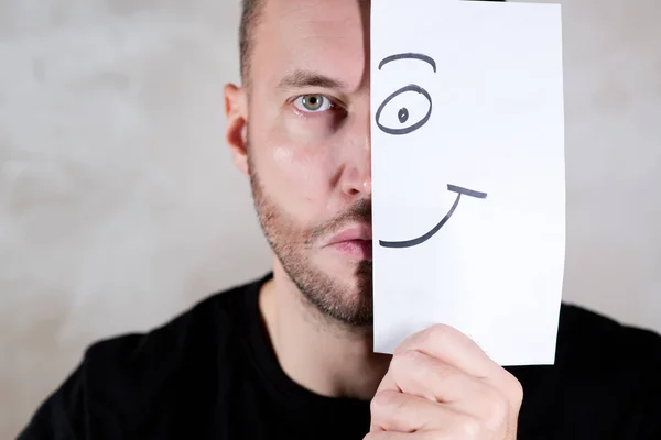 Hombre angustiado cubre la mitad de su cara con una sábana con una sonrisa pintada — Foto de Stock