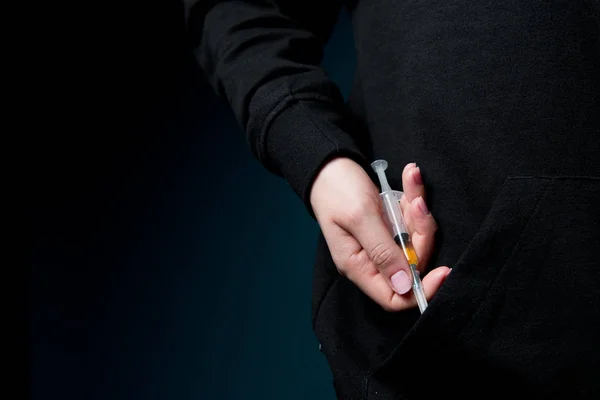 Samica wyciąga rękę z kieszeni i pokazuje strzykawkę wypełnioną płynem narkotycznym — Zdjęcie stockowe