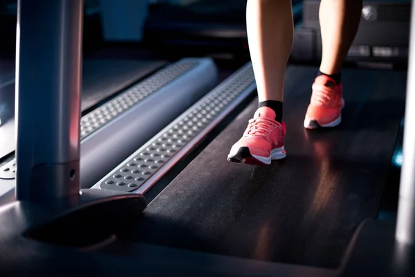 Piernas de una chica que se está calentando en una cinta de correr . — Foto de Stock