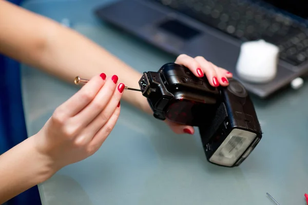 girl disassembles an electrical appliance, repairs photo flash.