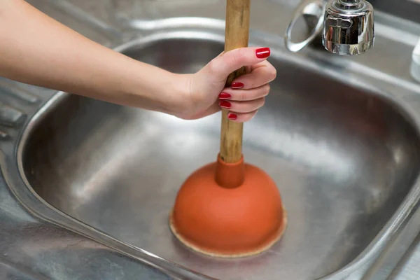 Chica va a limpiar el fregadero de la cocina con un émbolo —  Fotos de Stock
