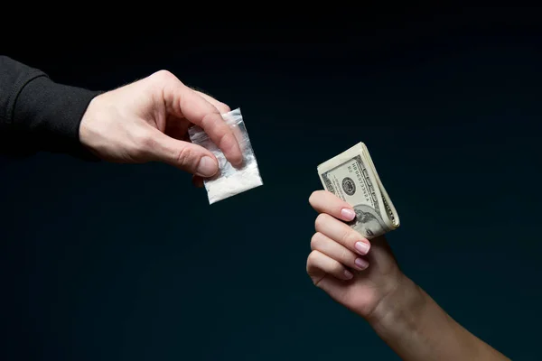 Las manos se atraen entre sí. En una mano, una bolsa de cocaína, en la otra mano dinero — Foto de Stock