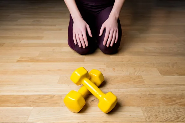 Ragazza seduta sul pavimento davanti ai manubri in palestra — Foto Stock